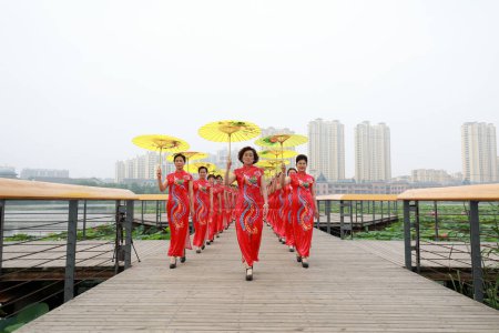 Photo for Luannan County, China - July 9, 2019: Women in red cheongsams are performing in a walk show, Luannan County, Hebei Province, China - Royalty Free Image