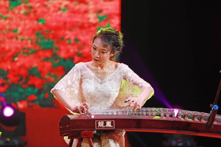 Foto de LUANNAN COUNTY, provincia de Hebei, China - 30 de diciembre de 2019: La interpretación de la tradicional música instrumental china de Guzheng en el escenario. - Imagen libre de derechos