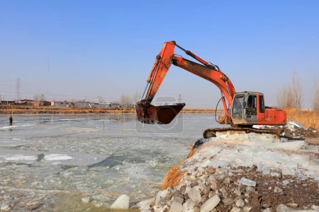 Photo for LUANNAN COUNTY, Hebei Province, China - January 14, 2020: Farmers use excavators to load ice in a factory - Royalty Free Image