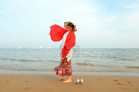 Photo for LUANNAN COUNTY, Hebei Province, China - May 3, 2019: A lady with a red shawl is playing by the sea. - Royalty Free Image