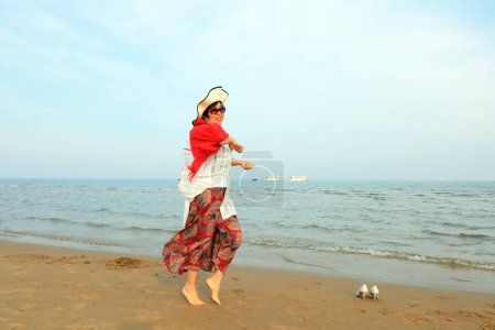 Téléchargez les photos : COMTÉ DE LUANNAN, Province du Hebei, Chine - 3 mai 2019 : Une dame au châle rouge joue au bord de la mer. - en image libre de droit