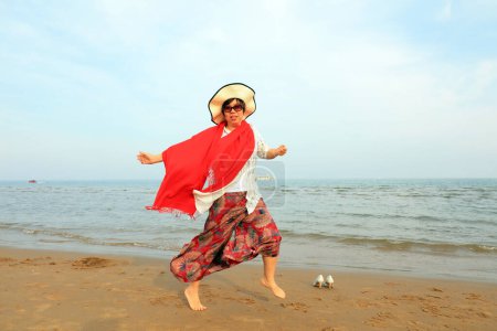 Téléchargez les photos : COMTÉ DE LUANNAN, Province du Hebei, Chine - 3 mai 2019 : Une dame au châle rouge joue au bord de la mer. - en image libre de droit