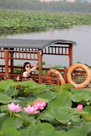 Foto de Condado de Luannan, China - 15 de julio de 2019: Los turistas fotografian flores de loto en un crucero, Condado de Luannan, provincia de Hebei, China - Imagen libre de derechos