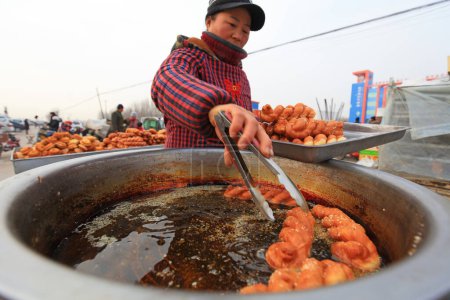 Téléchargez les photos : COMTÉ DE LUANNAN, Province du Hebei, Chine - 17 janvier 2020 : Un artisan fait Mahua sur place lors d'une foire rurale. - en image libre de droit
