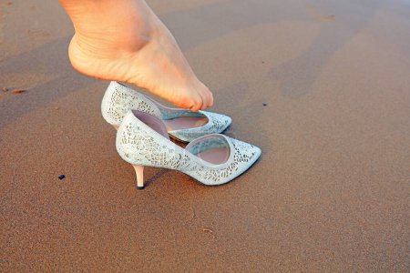 Foto de Los pies de las mujeres llevan tacones altos en la playa. - Imagen libre de derechos