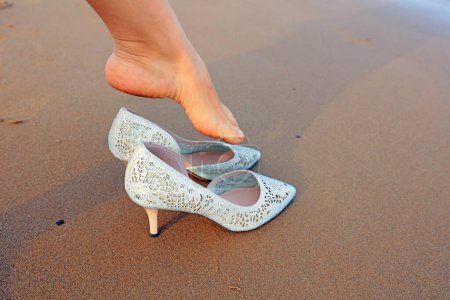 Téléchargez les photos : Les pieds des femmes portent des talons hauts sur la plage - en image libre de droit