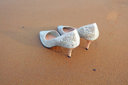 Photo for Women's white high heels on the wet beach - Royalty Free Image