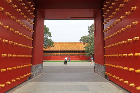 Téléchargez les photos : Les visiteurs jouent dans la porte du palais en bois rouge dans le parc Ditan, Pékin, Chine - en image libre de droit