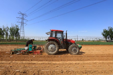 Téléchargez les photos : COMTÉ DE LUANNAN, province du Hebei, Chine - 5 mai 2019 : Les agriculteurs poussent les semoirs à cultiver des arachides paillées à la ferme. - en image libre de droit