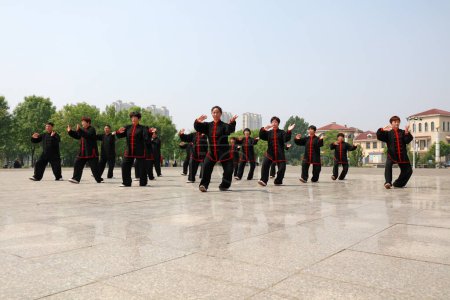 Foto de Ciudad de Tangshan, provincia de Hebei, China - 11 de mayo de 2019: Mucha gente de negro está practicando Taijiquan en el parque. - Imagen libre de derechos