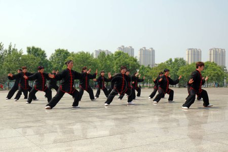 Foto de Ciudad de Tangshan, provincia de Hebei, China - 11 de mayo de 2019: Mucha gente de negro está practicando Taijiquan en el parque. - Imagen libre de derechos
