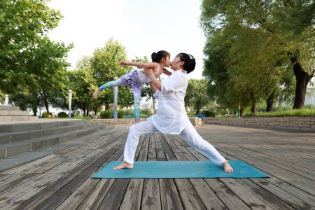 Téléchargez les photos : Comté de Luannan, Chine - 21 juin 2019 : Une dame et une petite fille pratiquant le yoga ensemble, comté de Luannan, province du Hebei, Chine. Ces dernières années, les exercices de yoga sont devenus de plus en plus populaires en Chine. - en image libre de droit