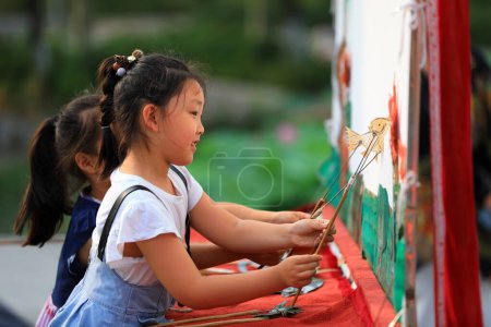 Photo for Luannan County, China - June 26, 2019: Primary school students learn Chinese shadow play manipulation in a park, Luannan County, Hebei Province, China. - Royalty Free Image