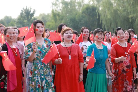 Téléchargez les photos : Comté de Luannan, Chine - 5 juillet 2019 : Des gens agitaient des drapeaux et chantaient des chansons patriotiques dans le parc, comté de Luannan, province du Hebei, Chine. - en image libre de droit