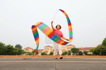 Foto de Condado de Luannan, China - 9 de julio de 2019: La gente agita cintas para ejercitarse en parques, Condado de Luannan, provincia de Hebei, China. Hoy en día, muchos chinos conceden gran importancia al ejercicio físico. - Imagen libre de derechos