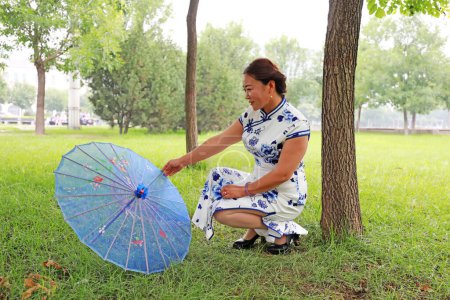 Foto de Condado de Luannan, China - 9 de julio de 2019: Mujeres en cheongsams juegan en el parque, Condado de Luannan, provincia de Hebei, China - Imagen libre de derechos
