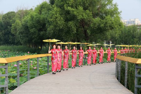 Photo for Luannan County, China - July 9, 2019: Women in red cheongsams are performing in a walk show, Luannan County, Hebei Province, China - Royalty Free Image