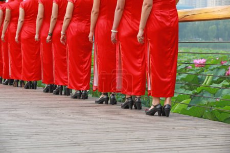 Photo for Women in red cheongsams are performing in a walk show, Luannan County, Hebei Province, China - Royalty Free Image