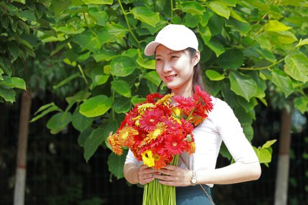 Téléchargez les photos : Comté de Luannan, Chine - 10 juillet 2019 : Une petite fille tenait des fleurs dans le parc, comté de Luannan, province du Hebei, Chine - en image libre de droit