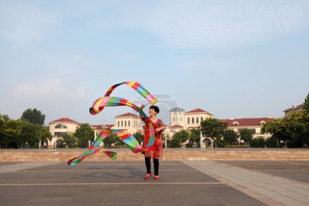 Téléchargez les photos : Comté de Luannan, Chine - 11 juillet 2019 : Des gens agitent des rubans pour faire de l'exercice dans les parcs, comté de Luannan, province du Hebei, Chine. De nos jours, beaucoup de Chinois attachent une grande importance à l'exercice physique. - en image libre de droit
