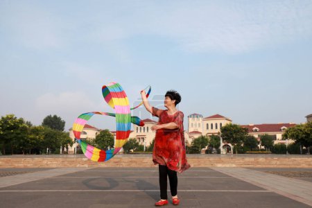 Foto de Condado de Luannan, China - 11 de julio de 2019: La gente agita cintas para ejercitarse en parques, Condado de Luannan, provincia de Hebei, China. Hoy en día, muchos chinos conceden gran importancia al ejercicio físico. - Imagen libre de derechos