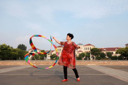 Foto de Condado de Luannan, China - 11 de julio de 2019: La gente agita cintas para ejercitarse en parques, Condado de Luannan, provincia de Hebei, China. Hoy en día, muchos chinos conceden gran importancia al ejercicio físico. - Imagen libre de derechos