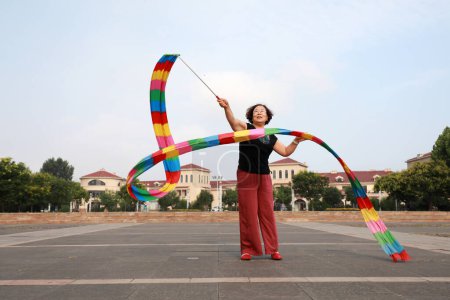 Photo for Luannan County, China - July 11, 2019: People wave ribbons to exercise in parks, Luannan County, Hebei Province, China. Nowadays, many Chinese people attach great importance to physical exercise. - Royalty Free Image