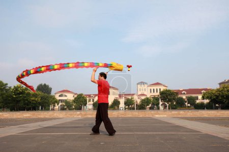 Photo for Luannan County, China - July 11, 2019: People wave Diabolo Dragon to exercise in parks, Luannan County, Hebei Province, China. Diabolo Dragon is one of the traditional Chinese folk fitness ways. - Royalty Free Image