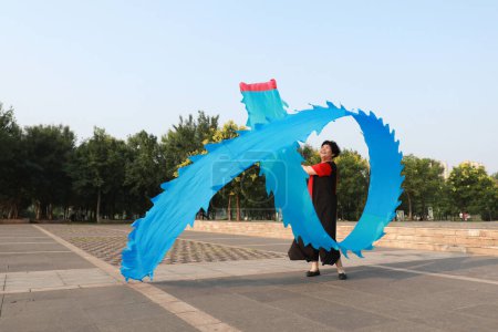 Téléchargez les photos : Comté de Luannan, Chine - 12 juillet 2019 : Des gens agitent des rubans pour faire de l'exercice dans les parcs, comté de Luannan, province du Hebei, Chine. De nos jours, beaucoup de Chinois attachent une grande importance à l'exercice physique. - en image libre de droit