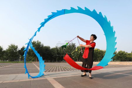 Photo for Luannan County, China - July 12, 2019: People wave ribbons to exercise in parks, Luannan County, Hebei Province, China. Nowadays, many Chinese people attach great importance to physical exercise. - Royalty Free Image
