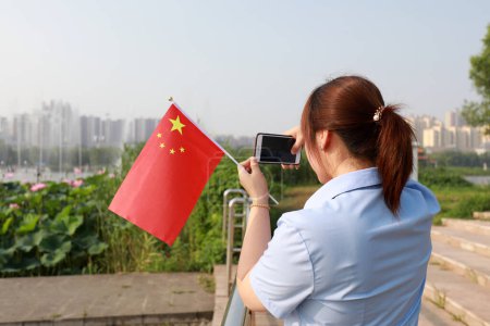 Téléchargez les photos : Comté de Luannan, Chine - 12 juillet 2019 : Les dames prennent des photos avec le drapeau national en main, comté de Luannan, province du Hebei, Chine - en image libre de droit
