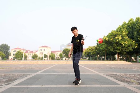 Photo for Luannan County, China - July 12, 2019: People wave Diabolo to exercise in parks, Luannan County, Hebei Province, China. Diabolo is one of the traditional Chinese folk fitness ways. - Royalty Free Image