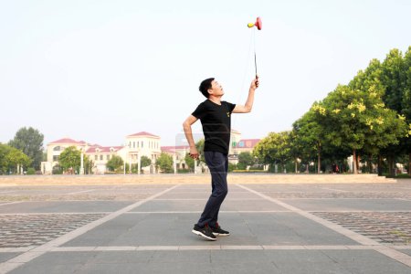 Foto de Condado de Luannan, China - 12 de julio de 2019: La gente agita Diabolo para ejercitarse en parques, Condado de Luannan, provincia de Hebei, China. Diabolo es una de las formas tradicionales de fitness popular chino. - Imagen libre de derechos