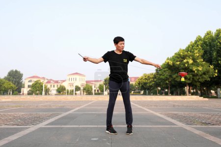 Foto de Condado de Luannan, China - 12 de julio de 2019: La gente agita Diabolo para ejercitarse en parques, Condado de Luannan, provincia de Hebei, China. Diabolo es una de las formas tradicionales de fitness popular chino. - Imagen libre de derechos