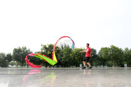 Photo for Luannan County, China - July 30, 2019: People wave ribbons to exercise in parks, Luannan County, Hebei Province, China. - Royalty Free Image