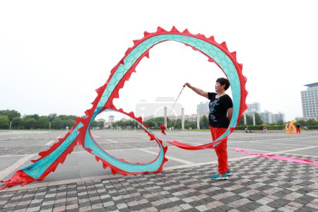 Téléchargez les photos : COMTÉ DE LUANNAN, Province du Hebei, Chine - 6 août 2019 : Des gens dansent de la soie colorée et s'entraînent sur la place du parc. - en image libre de droit