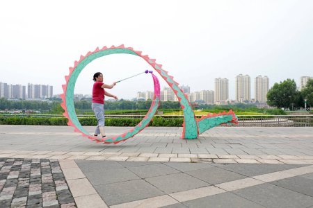 Foto de LUANNAN COUNTY, provincia de Hebei, China - 6 de agosto de 2019: La gente baila seda colorida y hace ejercicio en la plaza del parque. - Imagen libre de derechos