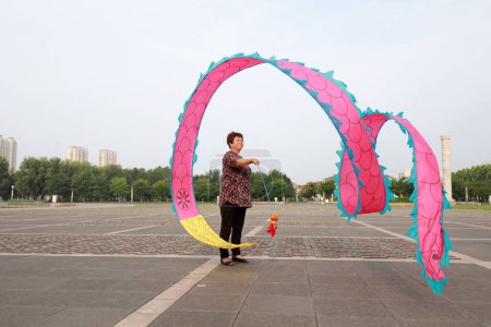 Téléchargez les photos : COMTÉ DE LUANNAN, Province du Hebei, Chine - 6 août 2019 : Des gens dansent de la soie colorée et s'entraînent sur la place du parc. - en image libre de droit