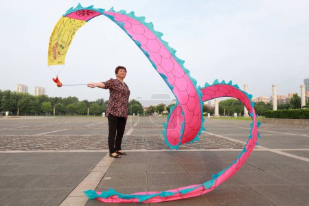 Foto de LUANNAN COUNTY, provincia de Hebei, China - 6 de agosto de 2019: La gente baila seda colorida y hace ejercicio en la plaza del parque. - Imagen libre de derechos