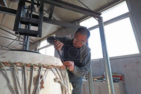 Photo for LUANNAN COUNTY - October 22, 2019: The drum maker is elaborately making cowhide drum, LUANNAN COUNTY, Hebei Province, China - Royalty Free Image