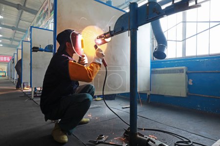 Foto de LUANNAN COUNTY, provincia de Hebei, China - 22 de noviembre de 2019: Los trabajadores están soldando piezas metálicas en la línea de producción. - Imagen libre de derechos