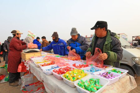 Foto de LUANNAN COUNTY, Provincia de Hebei, China - 17 de enero de 2020: Las personas que compran dulces están en el mercado rural. - Imagen libre de derechos