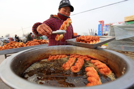 Téléchargez les photos : COMTÉ DE LUANNAN, Province du Hebei, Chine - 17 janvier 2020 : Un artisan fait Mahua sur place lors d'une foire rurale. - en image libre de droit
