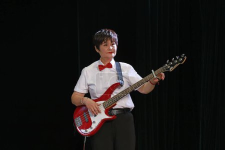 Photo for LUANNAN COUNTY, China - September 28, 2018: A woman is playing an electric guitar on a black background, LUANNAN COUNTY, Hebei Province, China - Royalty Free Image