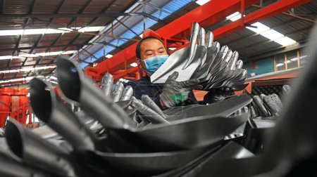 Foto de LUANNAN COUNTY - 27 de febrero de 2020: Trabajadores ocupados en la línea de producción de pulido de picas de acero, LUANNAN COUNTY, Hebei Province, Chin - Imagen libre de derechos