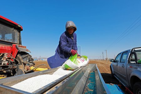 Foto de LUANNAN COUNTY, China - 4 de marzo de 2020: Los agricultores agregan fertilizante para semillas a Seeders, LUANNAN COUNTY, Hebei Province, China - Imagen libre de derechos