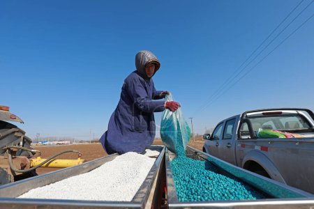 Foto de LUANNAN COUNTY, China - 4 de marzo de 2020: Los agricultores agregan fertilizante para semillas a Seeders, LUANNAN COUNTY, Hebei Province, China - Imagen libre de derechos