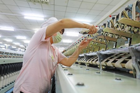 Foto de LUANNAN COUNTY, provincia de Hebei, China - 18 de marzo de 2020: Los trabajadores están reparando la maquinaria de hilado en la fábrica. - Imagen libre de derechos