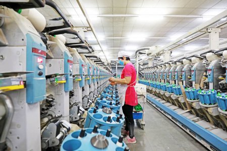 Téléchargez les photos : COMTÉ DE LUANNAN, Province du Hebei, Chine - 18 mars 2020 : La travailleuse est occupée sur la ligne de production dans une usine de filature. - en image libre de droit