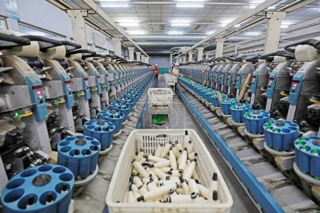 Foto de La trabajadora está ocupada en la línea de producción en una fábrica de hilado. - Imagen libre de derechos